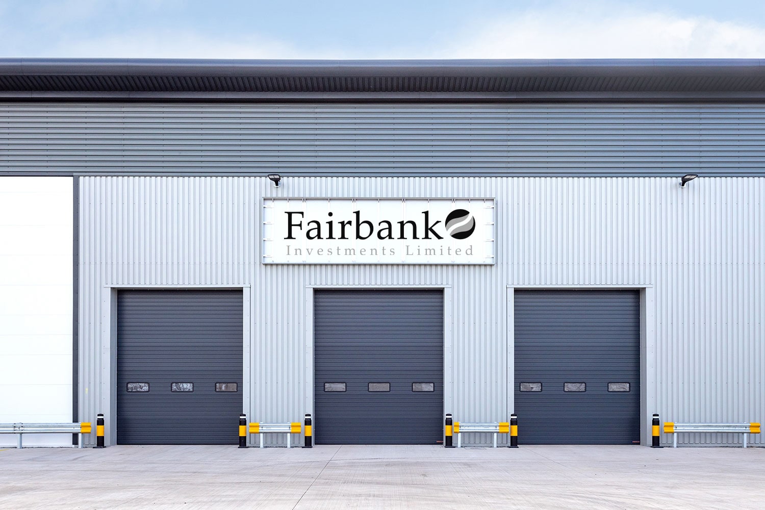 Modern industrial warehouse exterior with three closed roller shutter doors and protective bollards.