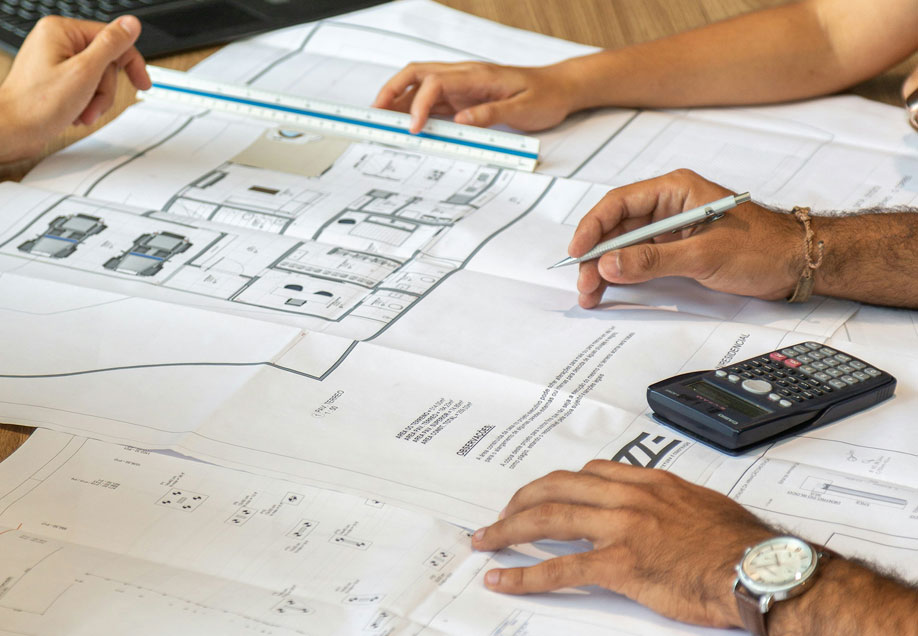 A close up of 3 people looking at planning documents and a floorplan.